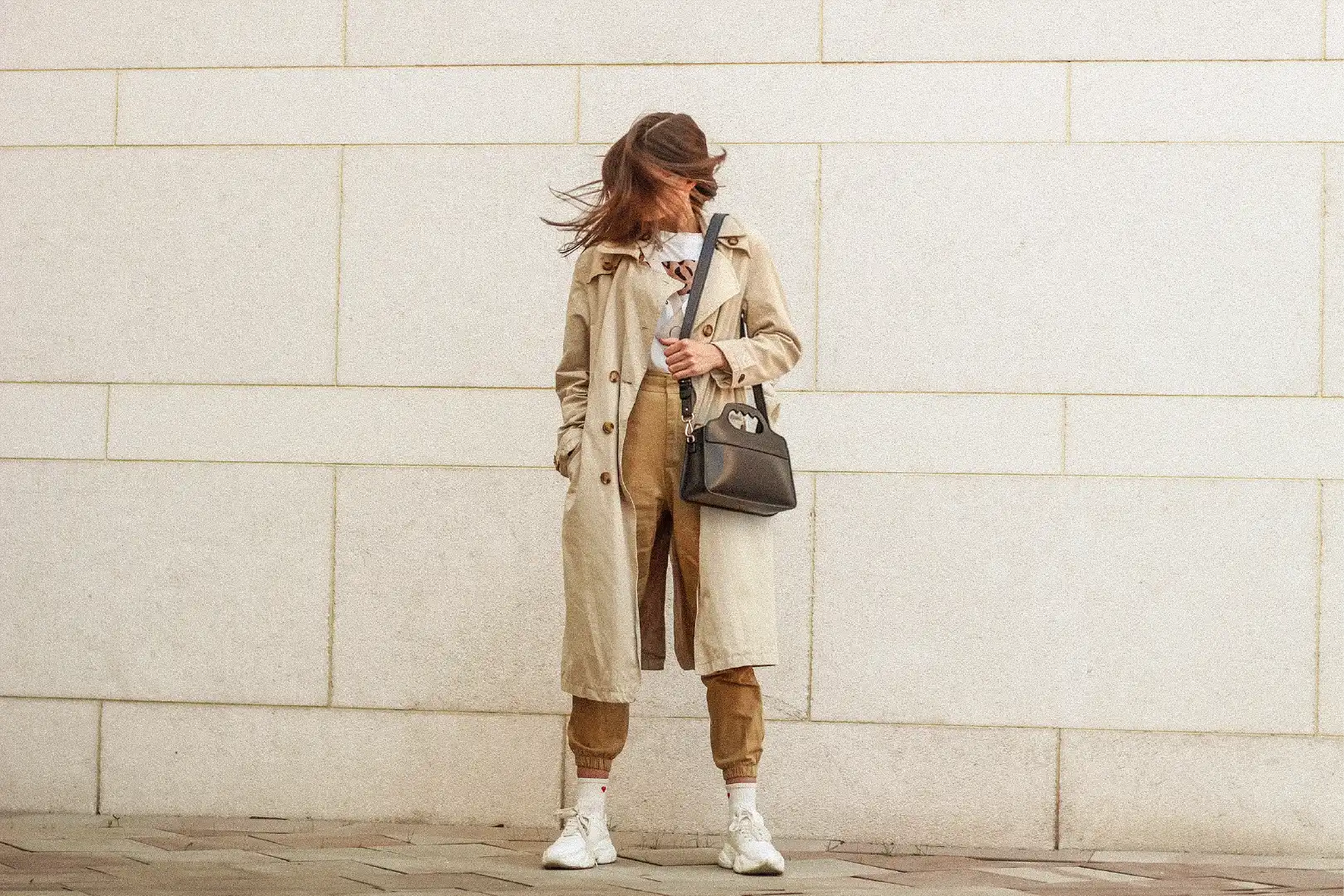 Femme posant devant un mur blanc avec un sac Lua à l'épaule