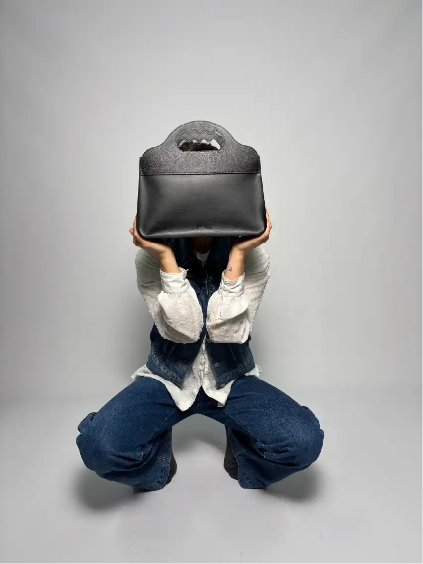 Une femme tenant un sac Lua devant son visage